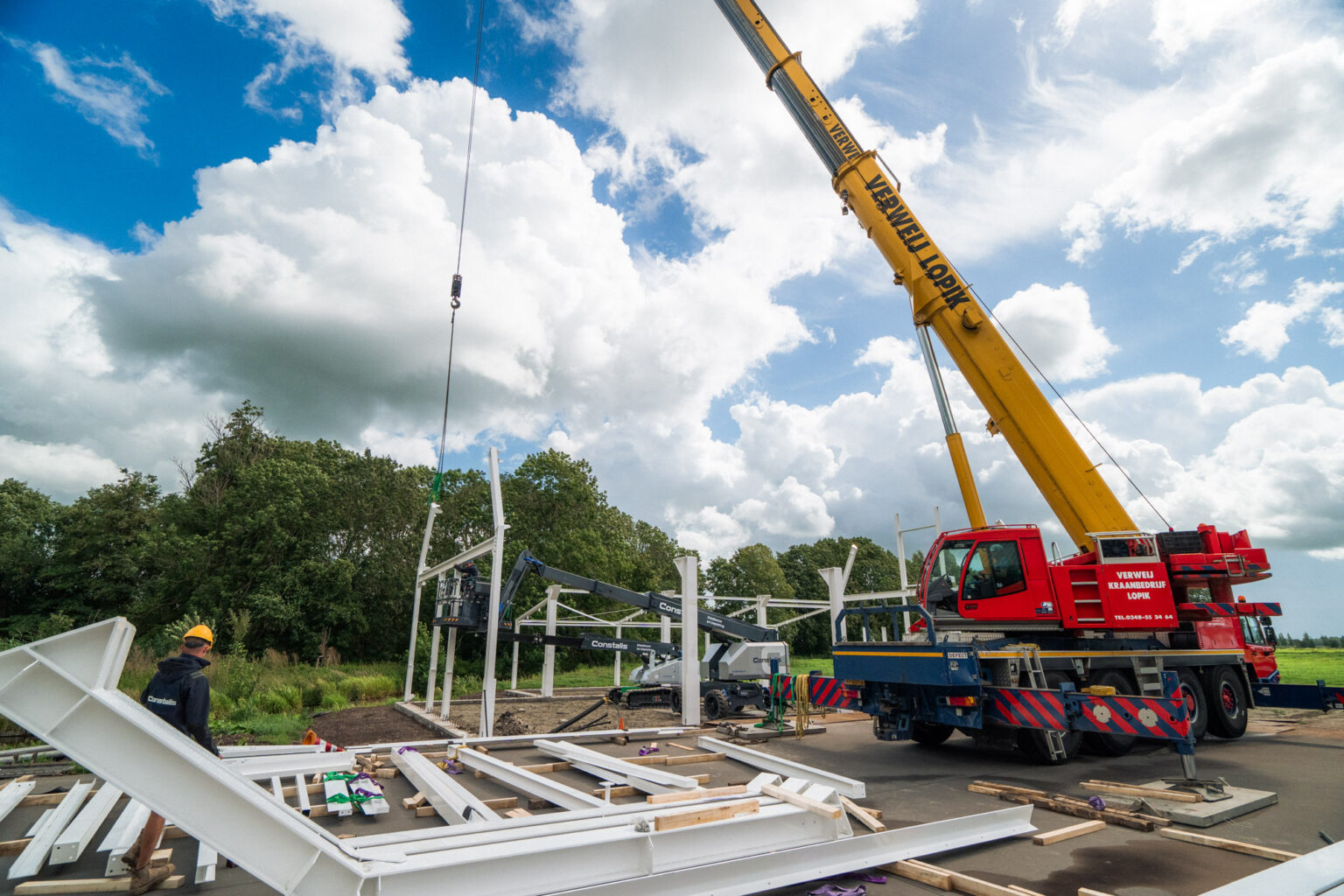 Bouwplaats met mobiele kraan en aangevoerd staal bij de start van de montage