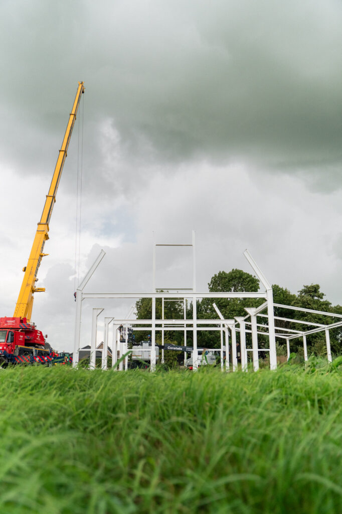 Staalconstructie in aanbouw met mobiele kraan op locatie