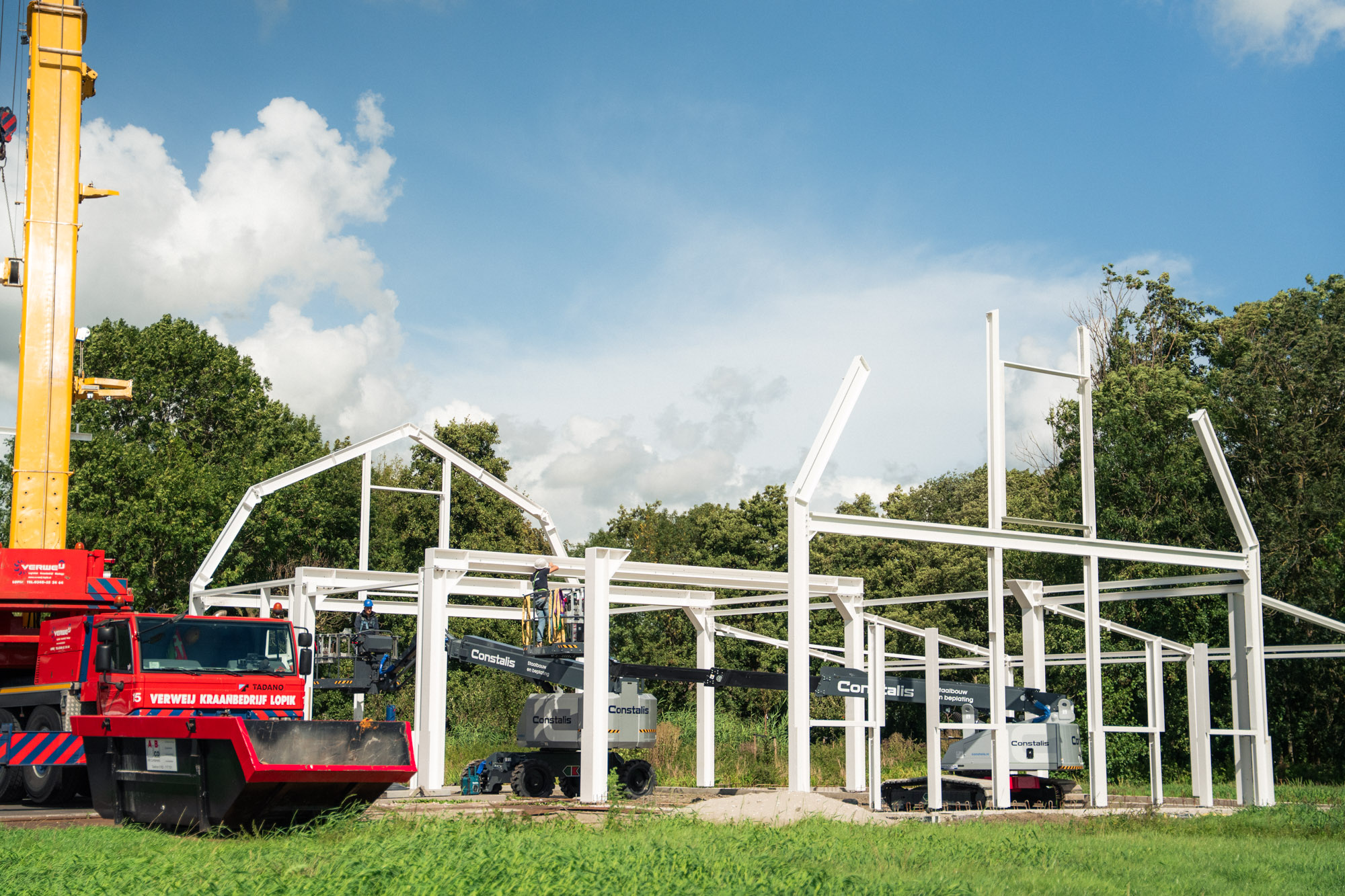 Bouwplaats met mobiele kraan en staalconstructie in aanbouw